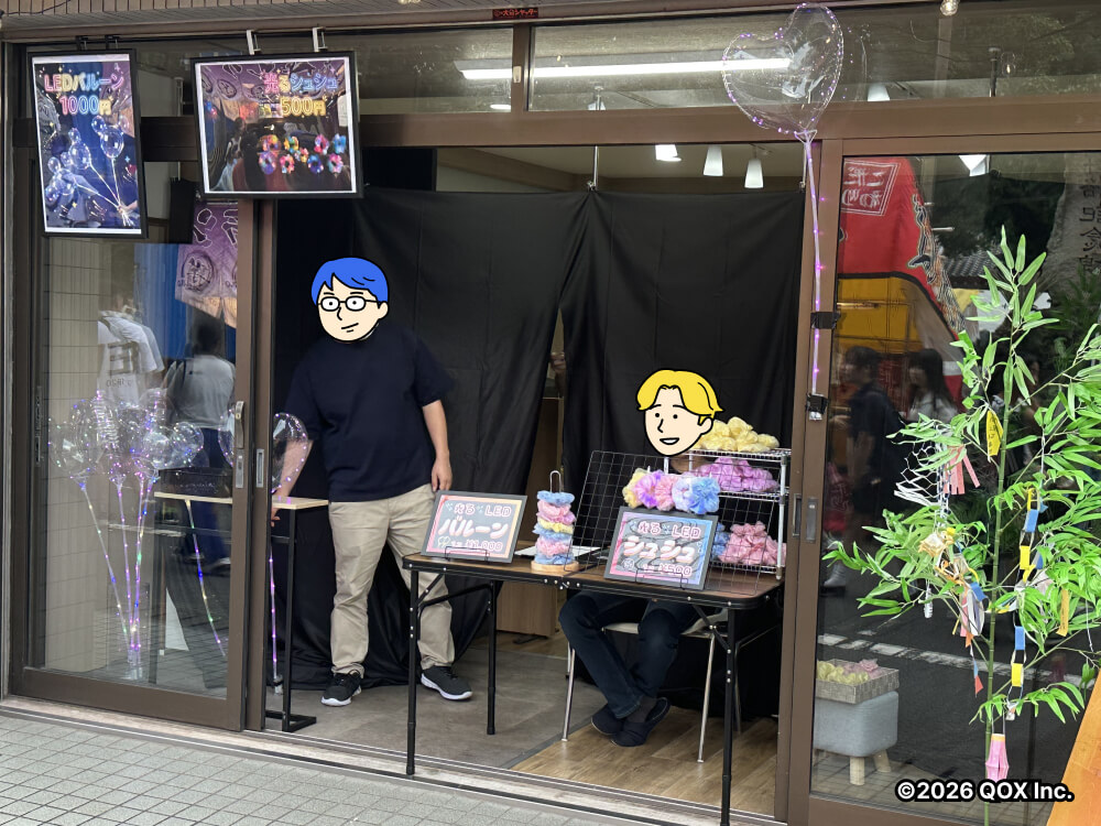 事務所の入口でお店が開けるようディスプレイ。後ろに暗幕、入り口の机にシュシュの棚をと値札を置き、スタッフが座っている