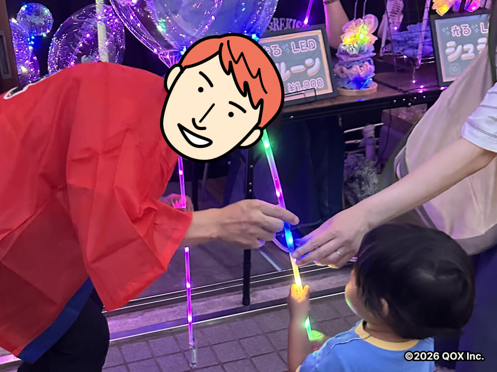 小さな男の子に光るバルーンを渡す代表